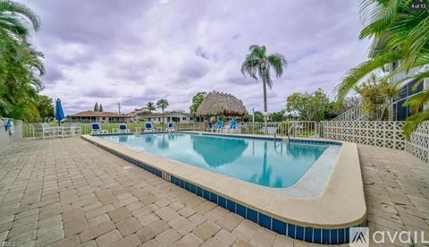 A swimming pool surrounded by a brick patio and palm trees.
