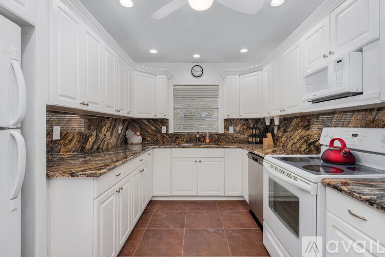 A kitchen with white cabinets and a granite countertop.