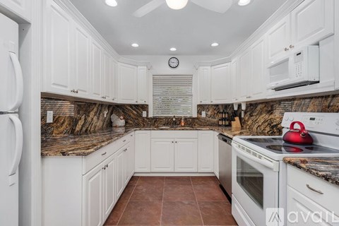 A kitchen with white cabinets and a granite countertop.