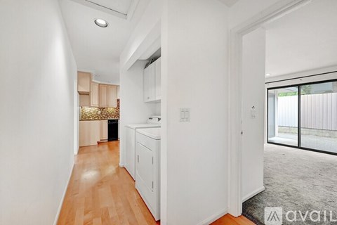 A kitchen area with white cabinets and a wooden floor.