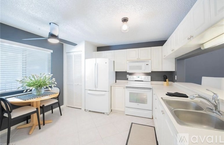 A kitchen with white appliances and a dining table with chairs.
