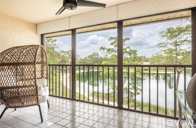 A balcony with a chair and a fan overlooking a body of water.