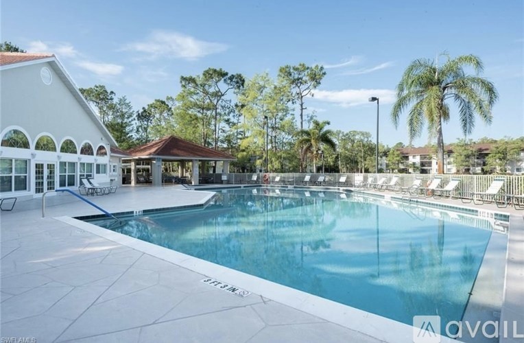 A large pool with a white building and palm trees in the background.