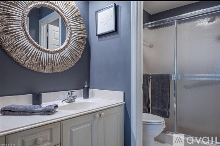 A bathroom with a mirror, sink, and towel.