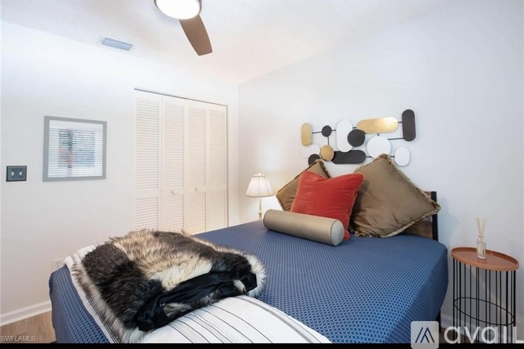 A bedroom with a bed, pillows, and a ceiling fan.