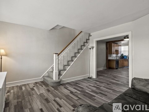 A living room with a grey couch and a wooden staircase.