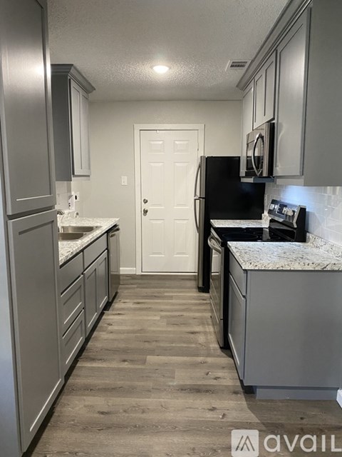 A kitchen with a black fridge and white cabinets.