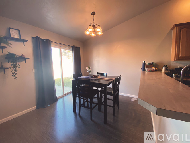 A dining room with a table set for two and a kitchen area with a countertop.