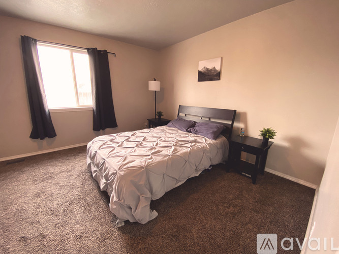 A bedroom with a bed, nightstand, and window.