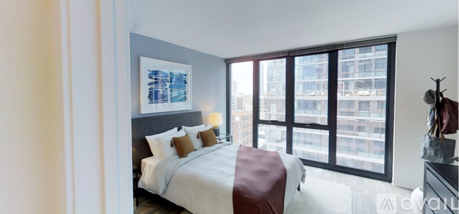 A bedroom with a large bed and a view of a cityscape through the window.