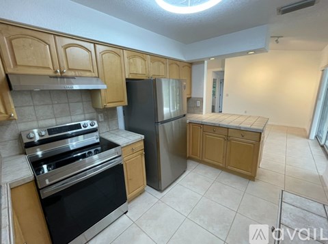 A kitchen with wooden cabinets and a black refrigerator.