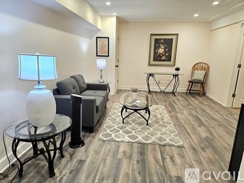 A living room with a grey sofa, a glass table, and a bicycle painting on the wall.