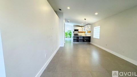 A spacious room with a kitchen area in the background.