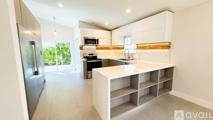 A modern kitchen with a refrigerator, microwave, oven, and sink.