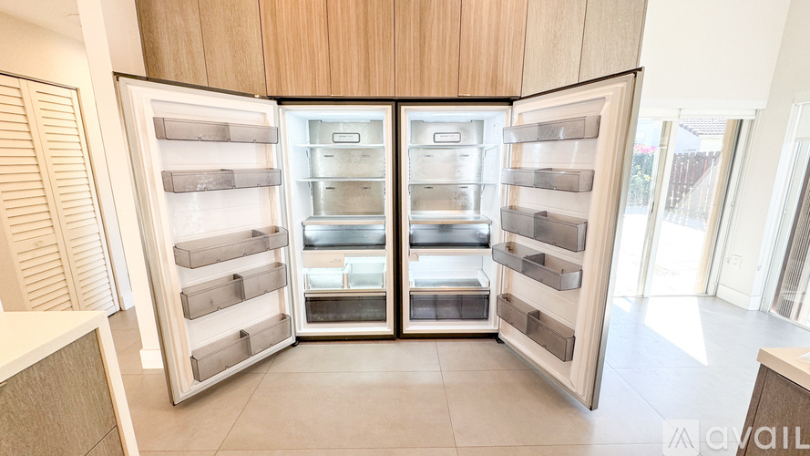 A modern kitchen with a large open refrigerator.