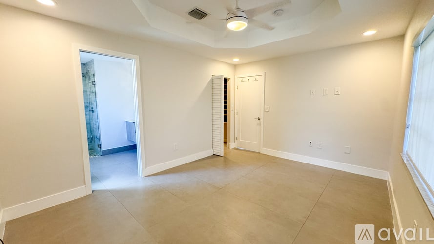 A spacious room with a ceiling fan and a door leading to another room.