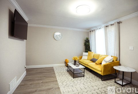 A living room with a yellow couch and a white coffee table.