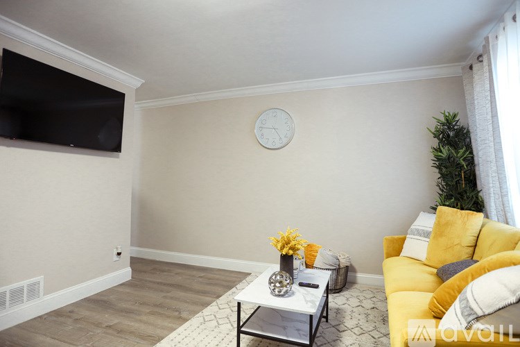 A living room with a yellow couch and a white coffee table.