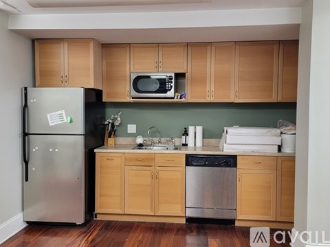 A kitchen with wooden cabinets and a stainless steel refrigerator.