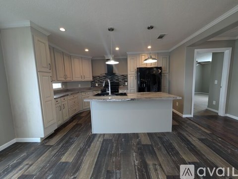 A kitchen with a white island in the middle of wooden floors.
