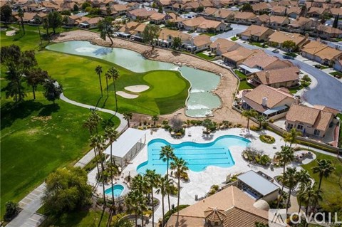 A golf course with a pool and houses in the background.