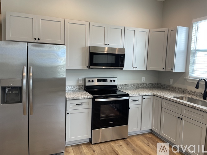 A kitchen with white cabinets and a stainless steel refrigerator.
