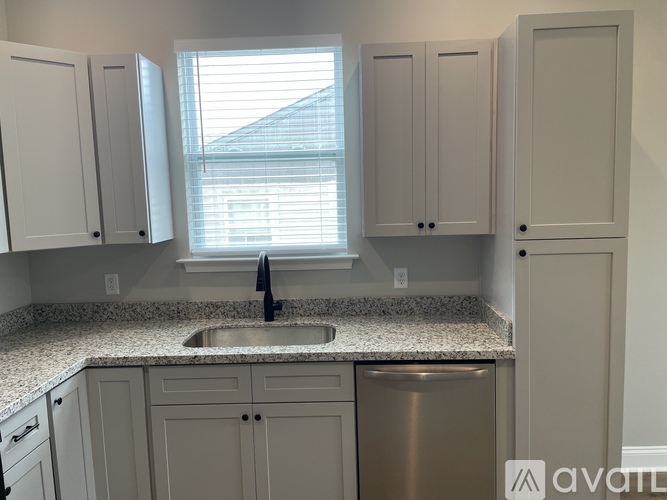 A kitchen with white cabinets and a granite countertop.