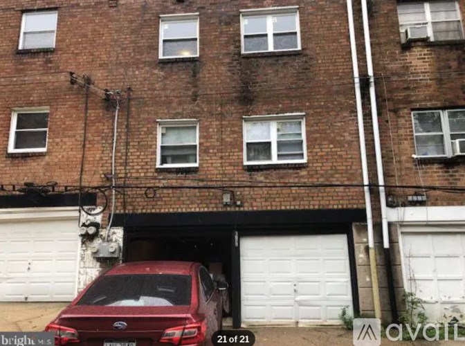 A red car is parked in front of a garage door.