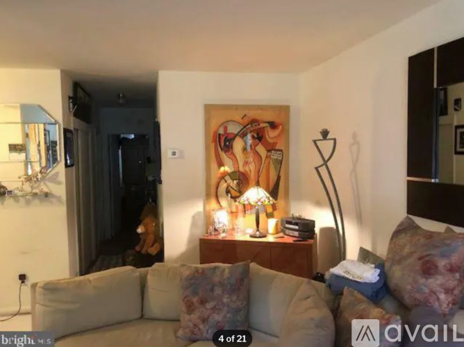 A living room with a couch, a lamp, and a painting on the wall.
