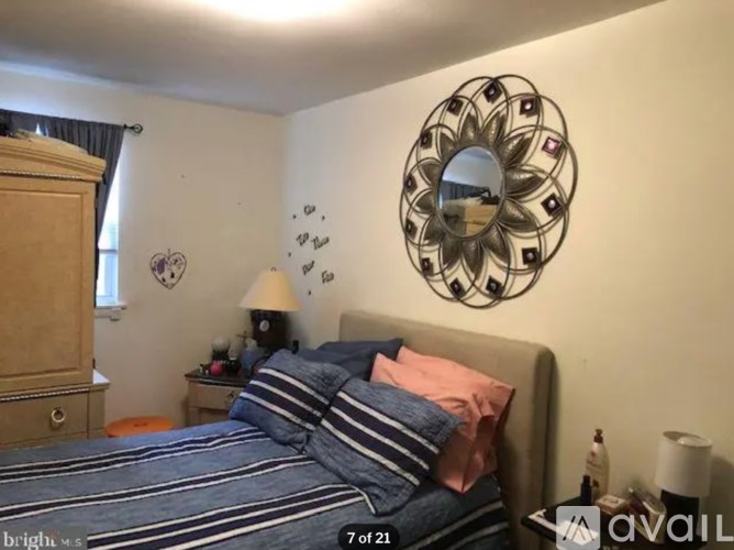 A bedroom with a bed, a mirror, and a lamp.