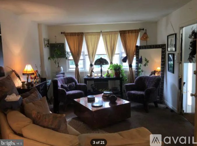 A living room with a sofa set, a coffee table, and a window with curtains.