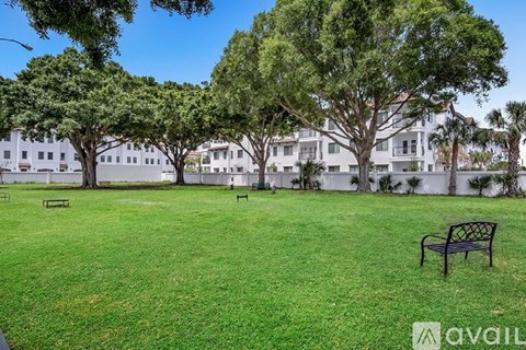 A grassy area with trees and benches in front of a white building.