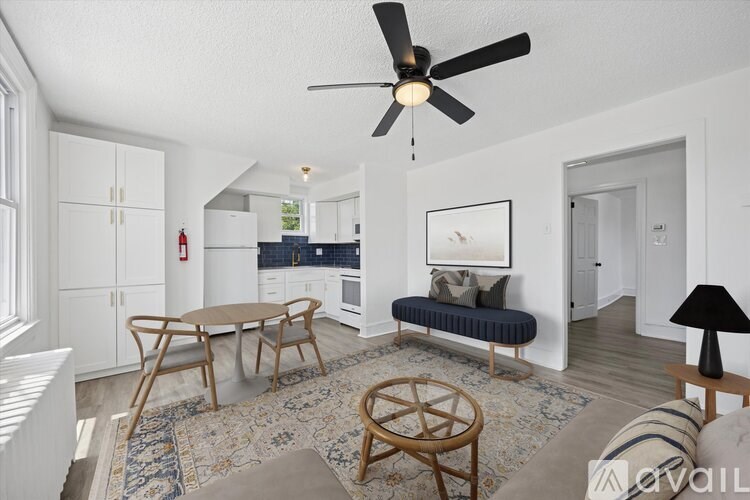 A living room with a ceiling fan and a rug on the floor.