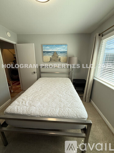 A bedroom with a single bed and a painting of a beach scene on the wall.