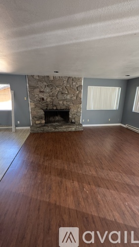 A room with a stone fireplace and wooden floors.