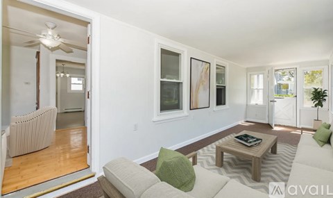 A living room with a white couch and a green pillow.