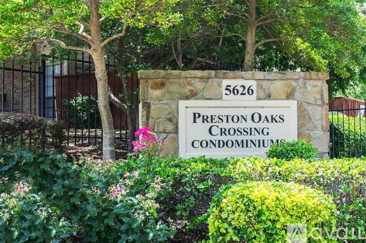 A sign for Preston Oaks Crossing Condominiums is surrounded by greenery.