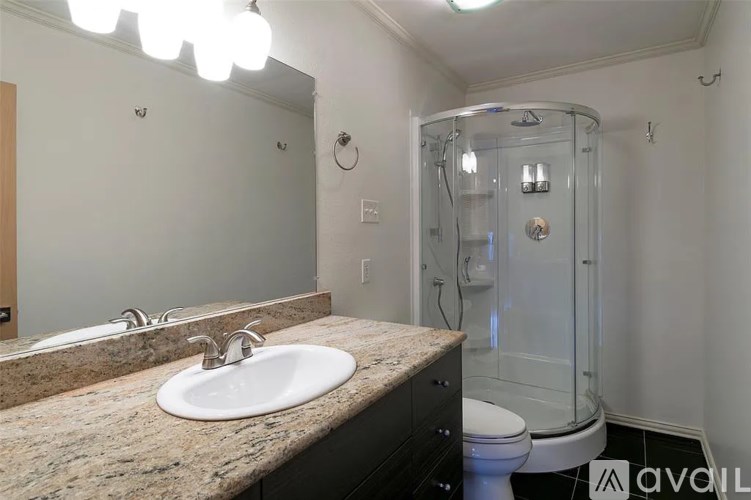 A bathroom with a sink, mirror, toilet and shower.