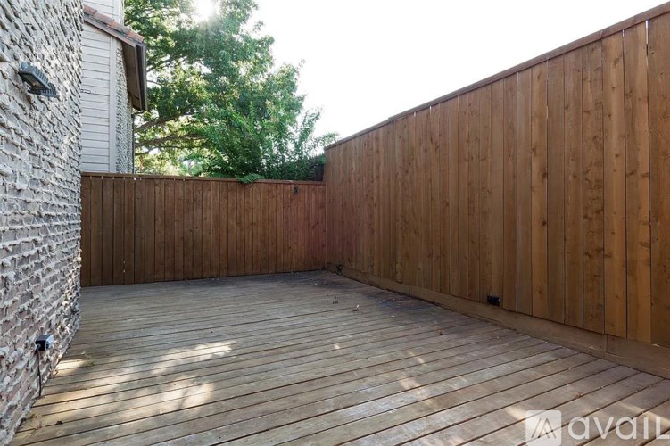 A wooden deck with a brick wall on one side and a wooden fence on the other.