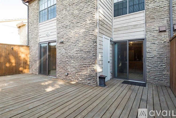 A wooden deck in front of a stone and wood building with a glass door.