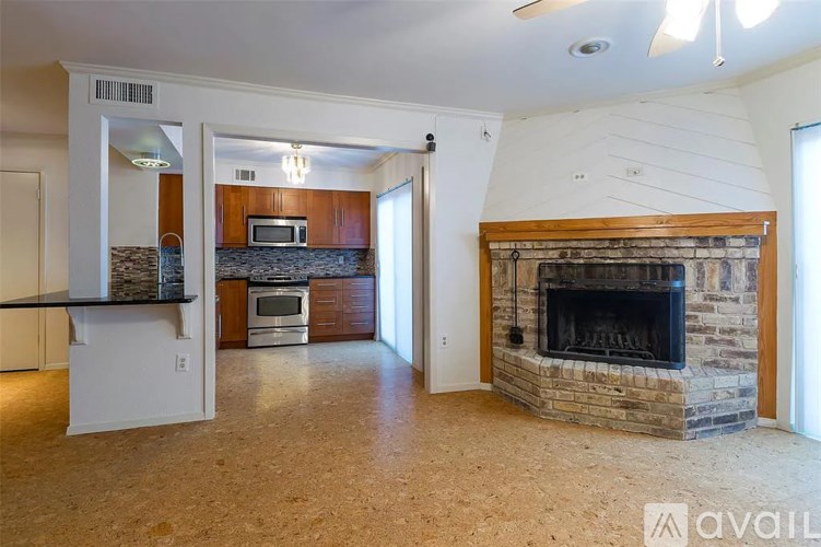 A living room with a stone fireplace and a kitchen area with a microwave and oven.