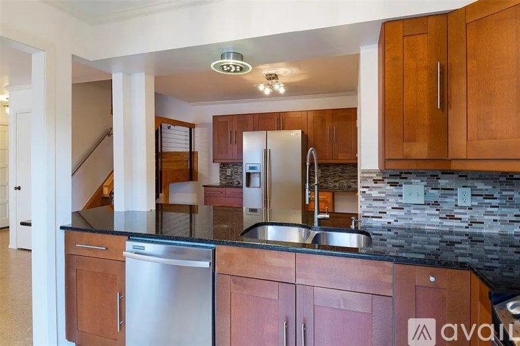 A kitchen with wooden cabinets and a stainless steel refrigerator.