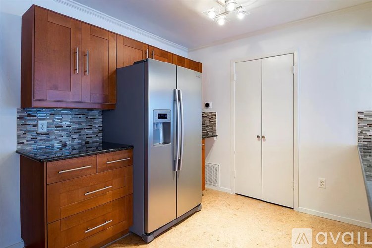 A kitchen with a stainless steel refrigerator and wooden cabinets.
