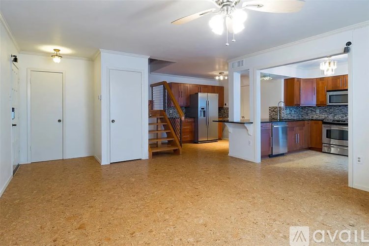 A spacious living room with a ceiling fan and a view into the kitchen.