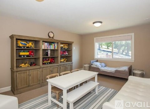 A living room with a white table and a large bookshelf filled with toy trucks.