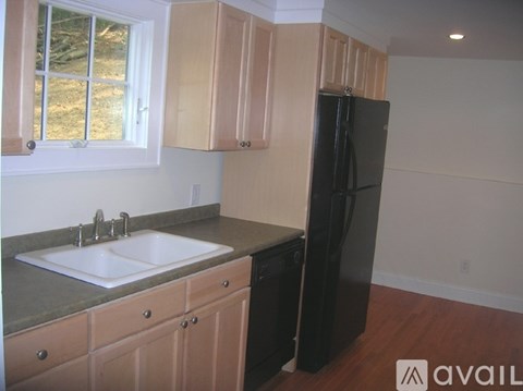 A kitchen with a black refrigerator and wooden cabinets.