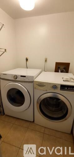 Two washing machines are in a room with a white wall.