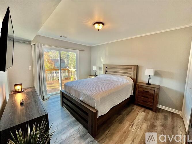 A bedroom with a large bed, a nightstand, and a window with curtains.