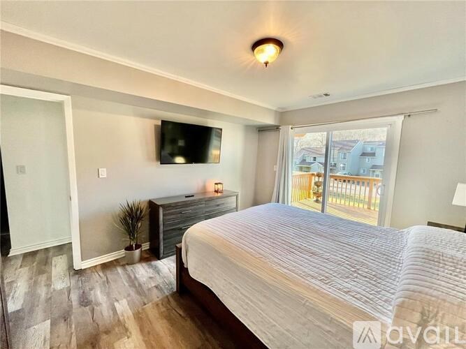 A bedroom with a large bed, a flat-screen TV, and a sliding glass door.
