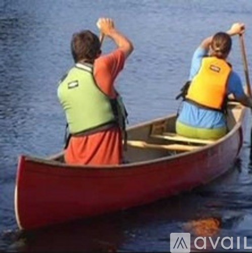 Two people in a canoe, one wearing a red shirt and the other in a blue shirt, paddling on a body of water.
